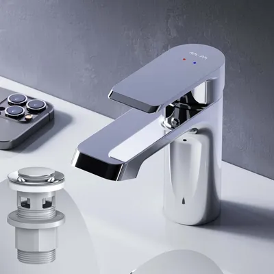 A close-up shot of a modern chrome faucet and a pop-up drain assembly on a white sink, with a gray textured wall in the background.
