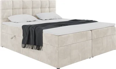 A boxspring bed with a headboard, mattress, and topper, with a blanket draped over it. The bed has storage drawers.