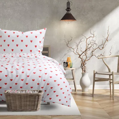 A bedroom scene with a bed dressed in heart-patterned bedding, a chair, and decorative branches.