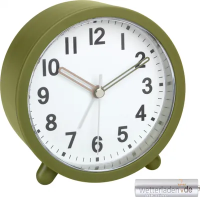 A close-up, front-facing view of a green analog alarm clock on a white background. A single AA battery is visible in the bottom right corner.