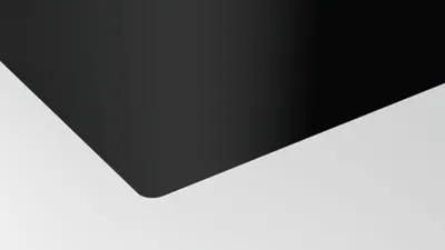 A close-up abstract shot of a black induction hob with a white background.