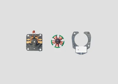 Three disassembled parts of a small electric motor are laid out on a plain gray background.