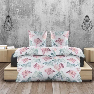 A bed with a butterfly-patterned duvet and pillows, set against a textured concrete wall.