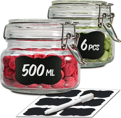 Two glass jars with clamp lids, one filled with red berries and labeled '500 ML', the other filled with green items and labeled '6 PCS'. A set of chalk-style labels and a marker are shown in the foreground.
