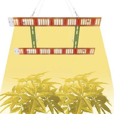 Two LED grow lights are suspended above a group of plants, casting a yellow glow.