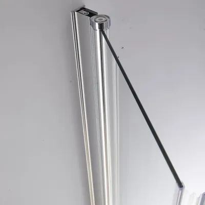 A close-up view of a shower enclosure's corner, showing the glass panel and its metallic frame against a plain background.