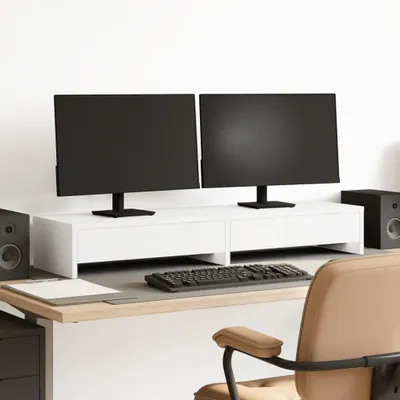 A clean, minimalist setup featuring a white monitor stand with two black monitors, a keyboard, and speakers on a wooden desk.