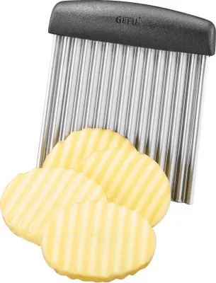 A wavy-edged slicer with several wavy-edged potato slices in front of it.