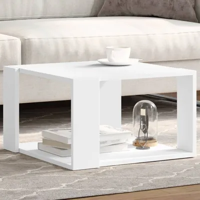 A white coffee table with books and a decorative item on it, placed in a living room setting next to a sofa.