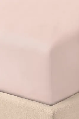 A close-up view of a pink fitted sheet draped over a beige bed skirt.