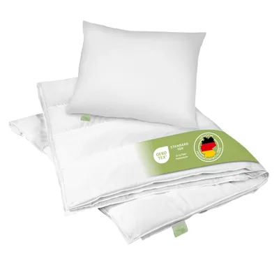 A white pillow and folded white duvet are arranged on a white background, with a green label attached to the duvet.