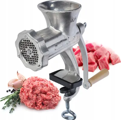 A manual meat grinder with raw meat, garlic, and herbs.