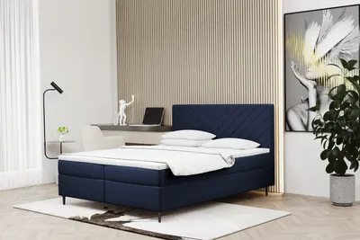 A bedroom scene with a bed, desk, and artwork.