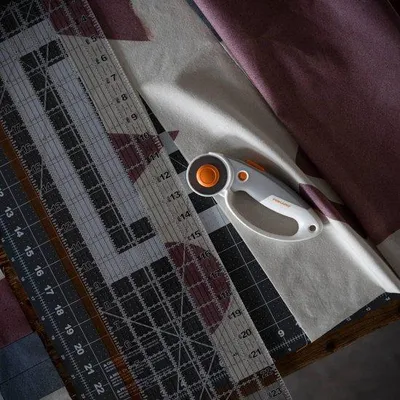 Zdjęcie produktu dla Unyqoos® Nóż do cięcia rolek Fiskars z ostrzem tytanowym, 45 mm – uchwyt pętelkowy z miękką powłoką SoftGrip, głębokość cięcia 7 mm, możliwość montażu z obu stron, odpowiedni zarówno dla osób praworęcznych, jak i leworęcznych, kolor: pomarańczowy/biały/szary