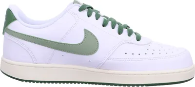 A side view of a white Nike Court Vision Low sneaker with green accents.