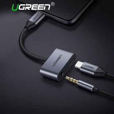 A Ugreen USB-C to 3.5mm audio adapter is shown connected to a smartphone, with a headphone jack and a USB-C charging cable plugged into the adapter.