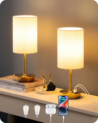 Two gold and beige bedside lamps with ribbed shades are displayed on a white shelf, with books and decorative items. Below the lamps, there are images of light bulbs, wireless earbuds, and a smartphone charging.