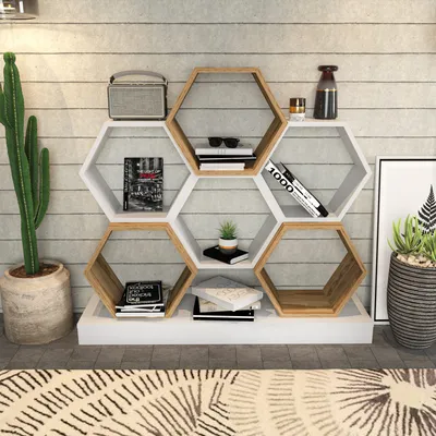 A hexagonal bookshelf filled with books and decorative items, placed against a wood-paneled wall.