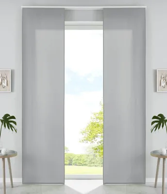 A pair of gray panel curtains are shown in a room, framing a view of trees and sky outside a window.