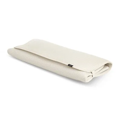 A beige UMBRA Abtropfmatte UDRY with a cutlery holder, folded and lying on a white background.