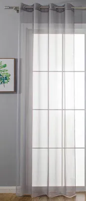 A sheer gray curtain hangs in front of a window with a grid pattern. A framed picture with green foliage is visible on the left.