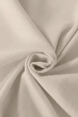 A close-up of beige fabric, folded and swirled.