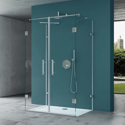 A modern shower enclosure with glass panels and chrome fixtures is shown in a bathroom setting with teal walls and concrete floors.