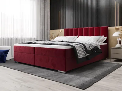A bedroom scene featuring a large red upholstered bed.