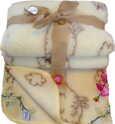 A folded sheep wool blanket tied with a burlap ribbon and decorated with artificial flowers.