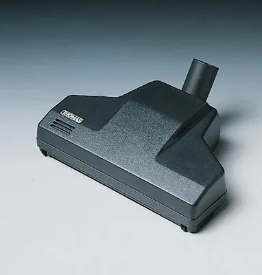 A dark gray vacuum cleaner attachment is shown on a light gray surface against a gradient background.