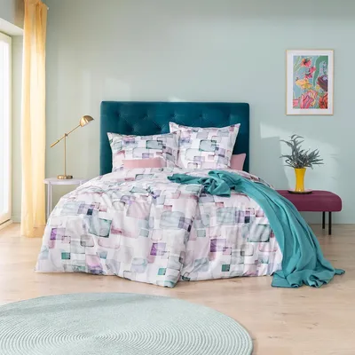 A bedroom scene with a bed, bedding, and decorative items.