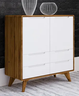 A white and wood dresser against a black brick wall, with decorative vases on top.