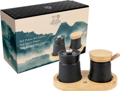 A product box and set of spice grinders on a wooden tray.