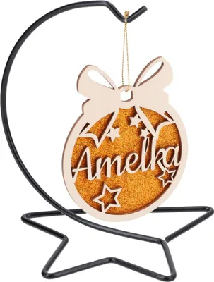 A wooden Christmas ornament with the name 'Amelka' on it, displayed on a black metal stand.