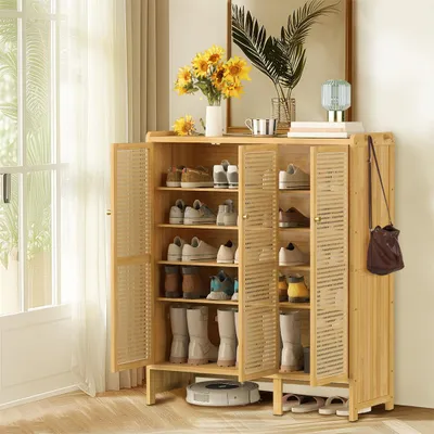 A wooden shoe cabinet filled with shoes, placed in a room with natural light coming from a window.
