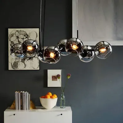 A modern living room setting with a chandelier, artwork, and decorative items on a shelf.
