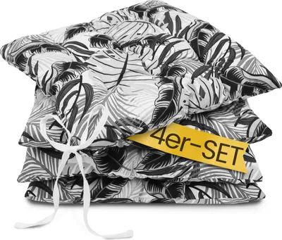 A stack of four seat cushions with a tropical leaf pattern, tied together with a white ribbon. A yellow tag with black text is attached to the cushions.