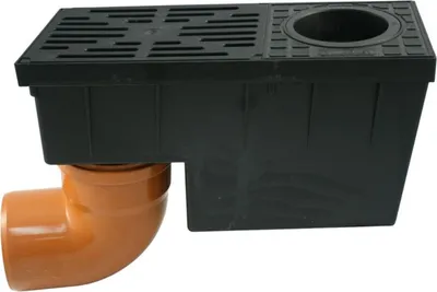 A black drainage box with a grate and a circular opening, connected to an orange pipe elbow.