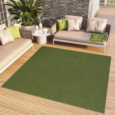 An outdoor patio setting with furniture and a rug.