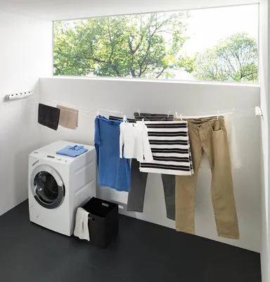A laundry room with a washing machine and clothes drying on a retractable clothesline.