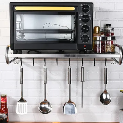 A kitchen shelf with an oven and hanging utensils.