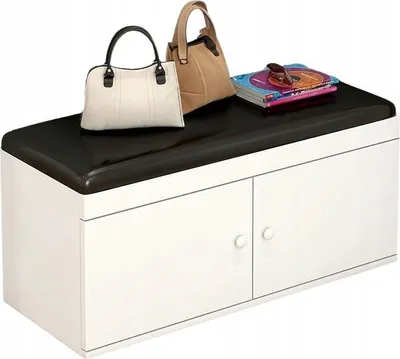 A white shoe cabinet with a black padded top, decorated with two handbags and a stack of books.