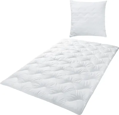 A white duvet and pillow set laid out on a white background.