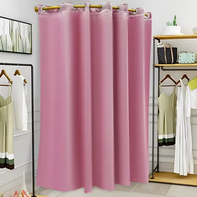 A pink changing room curtain with clothes hanging on racks nearby.