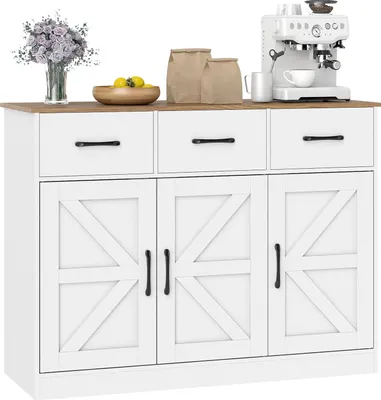 A white sideboard with a wooden top, featuring three drawers and three cabinet doors with a barn door design. It is decorated with a vase of flowers, a bowl of lemons, and two paper bags on top, along with a white espresso machine.