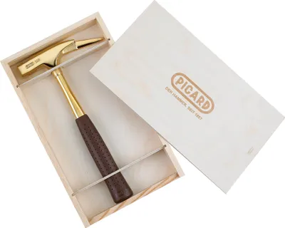 A golden hammer with a brown handle is displayed in a wooden box, with the lid open and resting behind it. The lid has the brand name 'PICARD' embossed on it.
