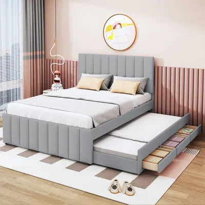 A grey upholstered bed with a pull-out trundle bed and storage drawers, set in a bedroom with pink and grey decor.