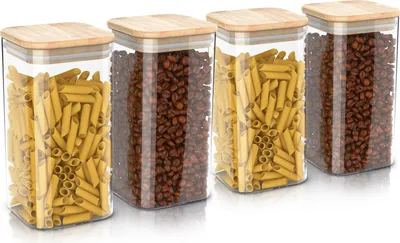Four glass storage jars with bamboo lids, filled with pasta and coffee beans, are arranged in a row on a white background.