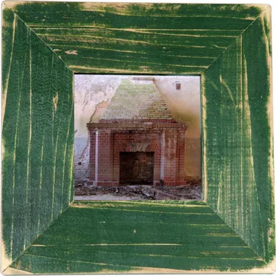 A framed picture of an old, brick fireplace inside a derelict building.