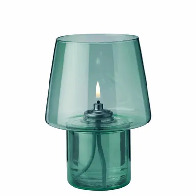 A green glass oil lamp with a lit wick, shown against a white background.